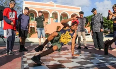 Dançarino de breaking se apresenta em espaço público cercado pelo público